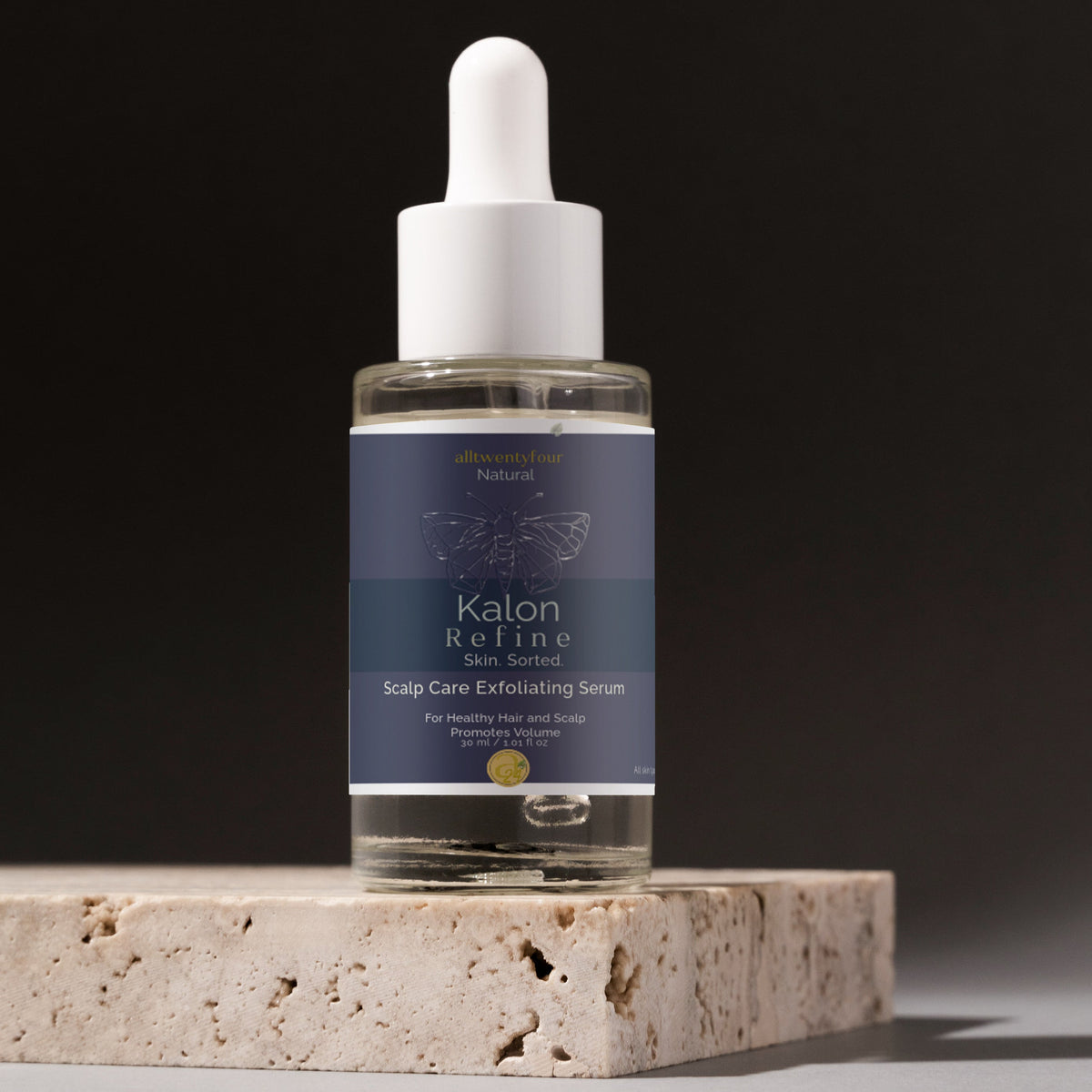 Skincare Kalon scalp serum bottle with dropper on a stone surface against a dark background